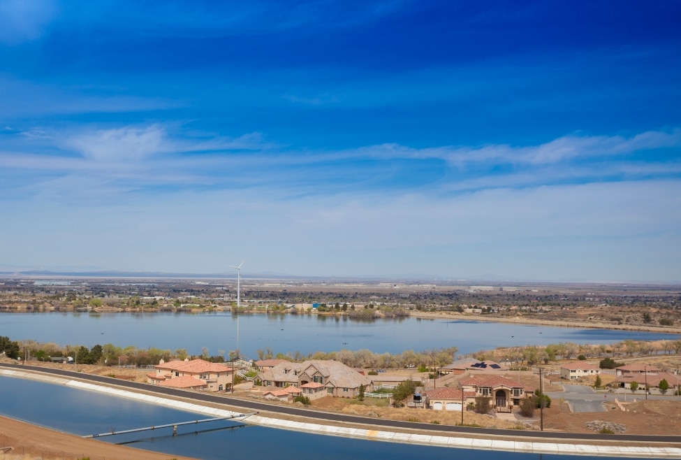 A scenic view of Lake Palmdale and surrounding homes with a wind turbine in the distance under a clear blue sky. This image represents the tranquil residential areas served by Arctic Air, providing HVAC services such as air conditioning repair, heating solutions, and energy-efficient installations for homeowners in Palmdale and the surrounding Southern California areas. Lake Palmdale, scenic view, residential community, Southern California, Palmdale CA, wind turbine, desert landscape, energy efficiency, HVAC services, Arctic Air AV, cooling solutions, heating services, air conditioning repair, HVAC installation, residential HVAC, commercial HVAC, Palmdale home comfort.